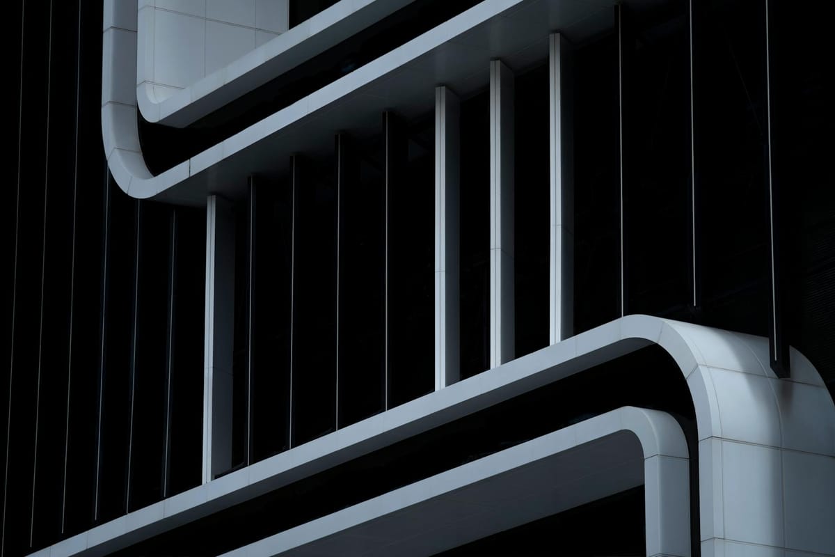 Close-up of a modern building facade featuring smooth white curves and vertical lines.