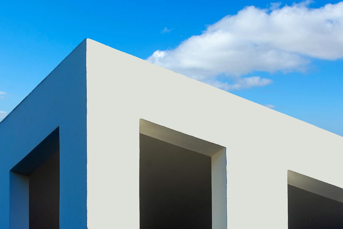Modern minimalist architecture with white facade and clear blue sky background.
