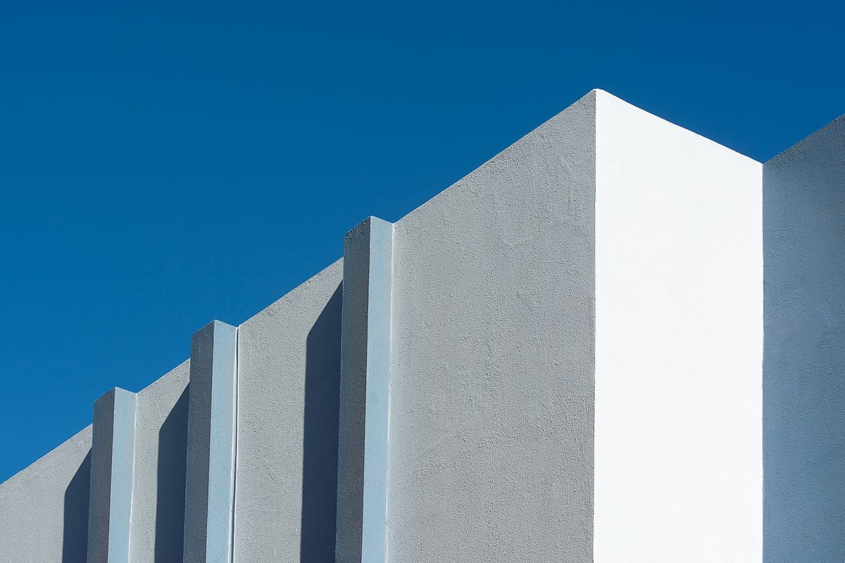 Minimalist view of a modern building facade with clean lines against a clear blue sky.