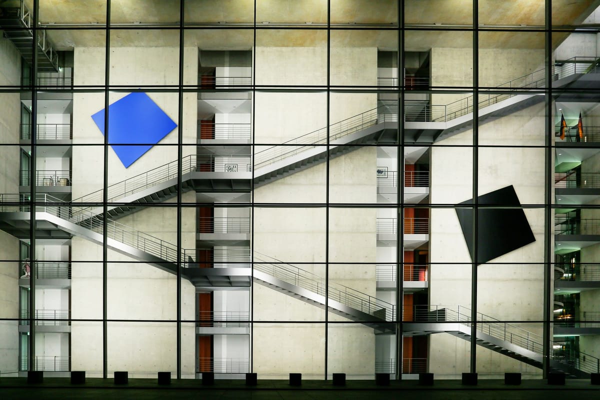 Contemporary glass building facade featuring diagonal staircases and geometric art.