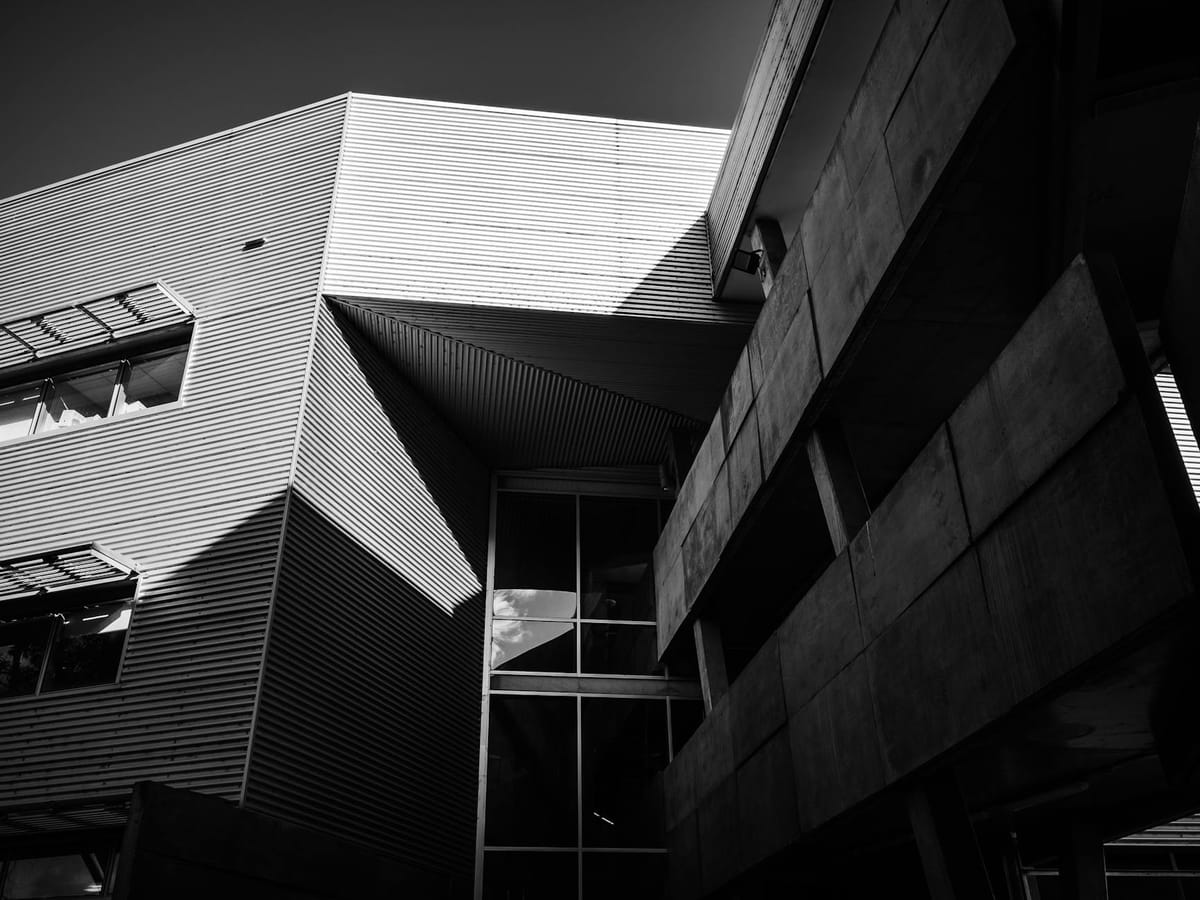 Low angle black and white shot of a modern building facade with glass windows.